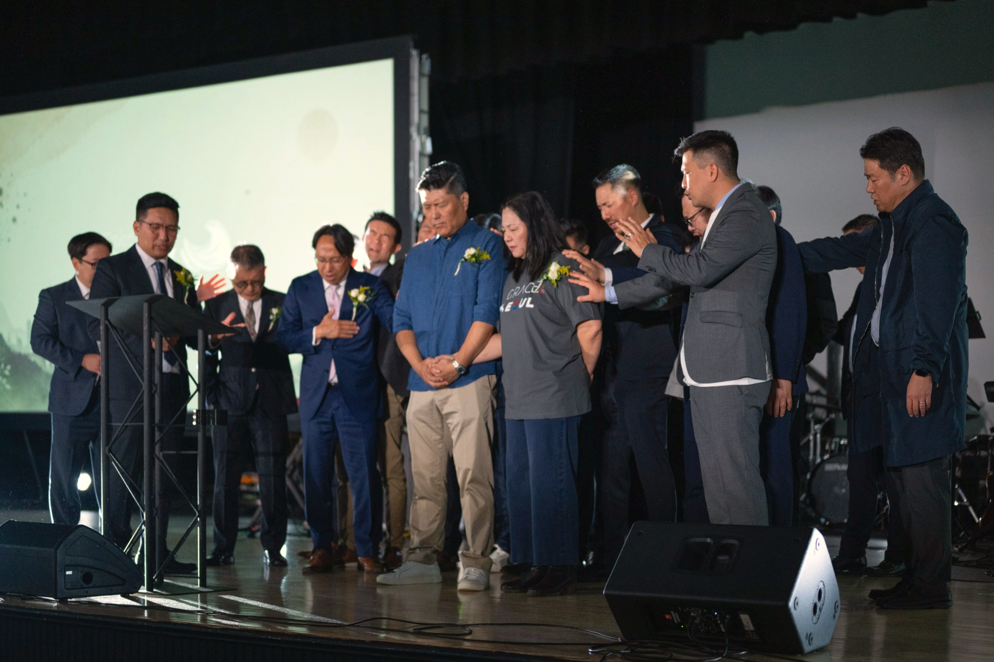 The congregation laying hands on the team being sent to Seoul